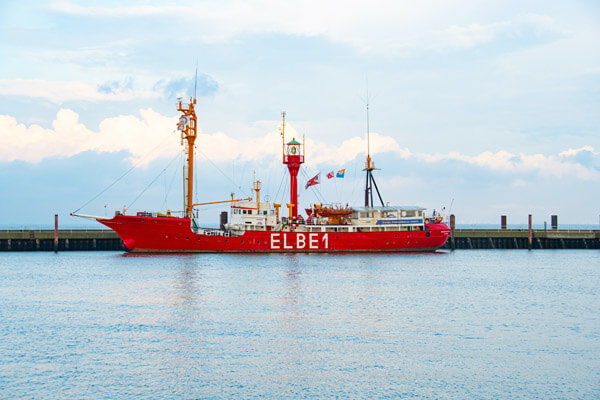 Feuerschiff Elbe 1 Schiff liegt am Kai im Hafen auf flachem Wasser im Hintergrund blaue Wolkenformationen, Location für Firmenjubiläum in Hamburg und Umgebung