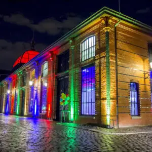 Fischauktionshalle die Wasserseite bei Nacht, festlich bunt beleuchtet mit bunten Luftballons und Kopfsteinpflaster im Vordergrund