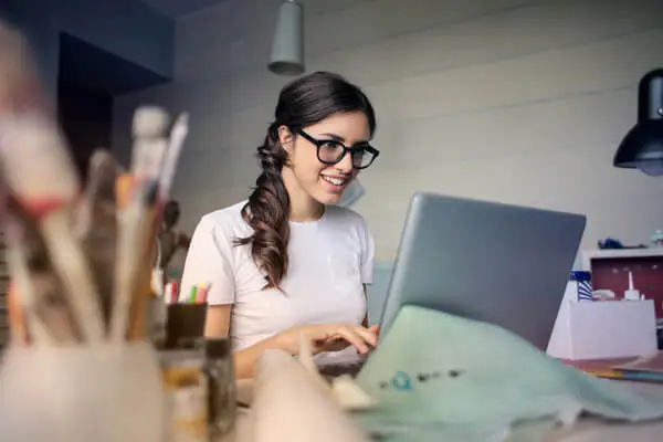 junge Frau im Homeoffice bei der Arbeit, lächelt in den Bildschirm erfolgreiche Hybrid Events in Hamburg