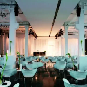 Prototyp Loft Museum weißer Saal mit Bühne, davor moderne Designstühle im Industrieloft Design