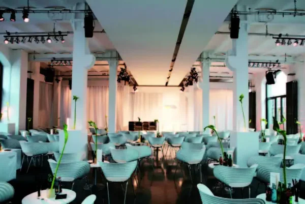 Prototyp Loft Museum weißer Saal mit Bühne, davor moderne Designstühle im Industrieloft Design