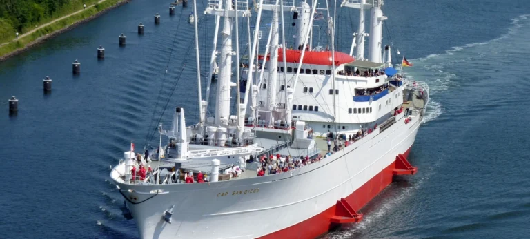 Museumsschiff Cap San Diego bei Fahrt auf der Elbe bei Sonnenschein und mit Menschen an Deck